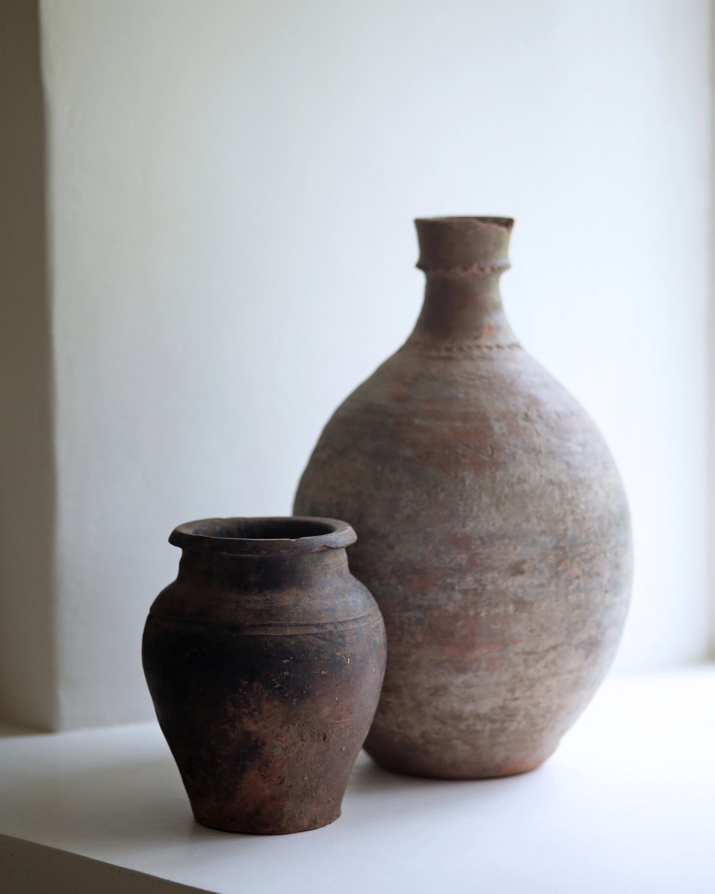 Pairing of antique pottery homeware pieces with decorative details and displayed on a window sill
