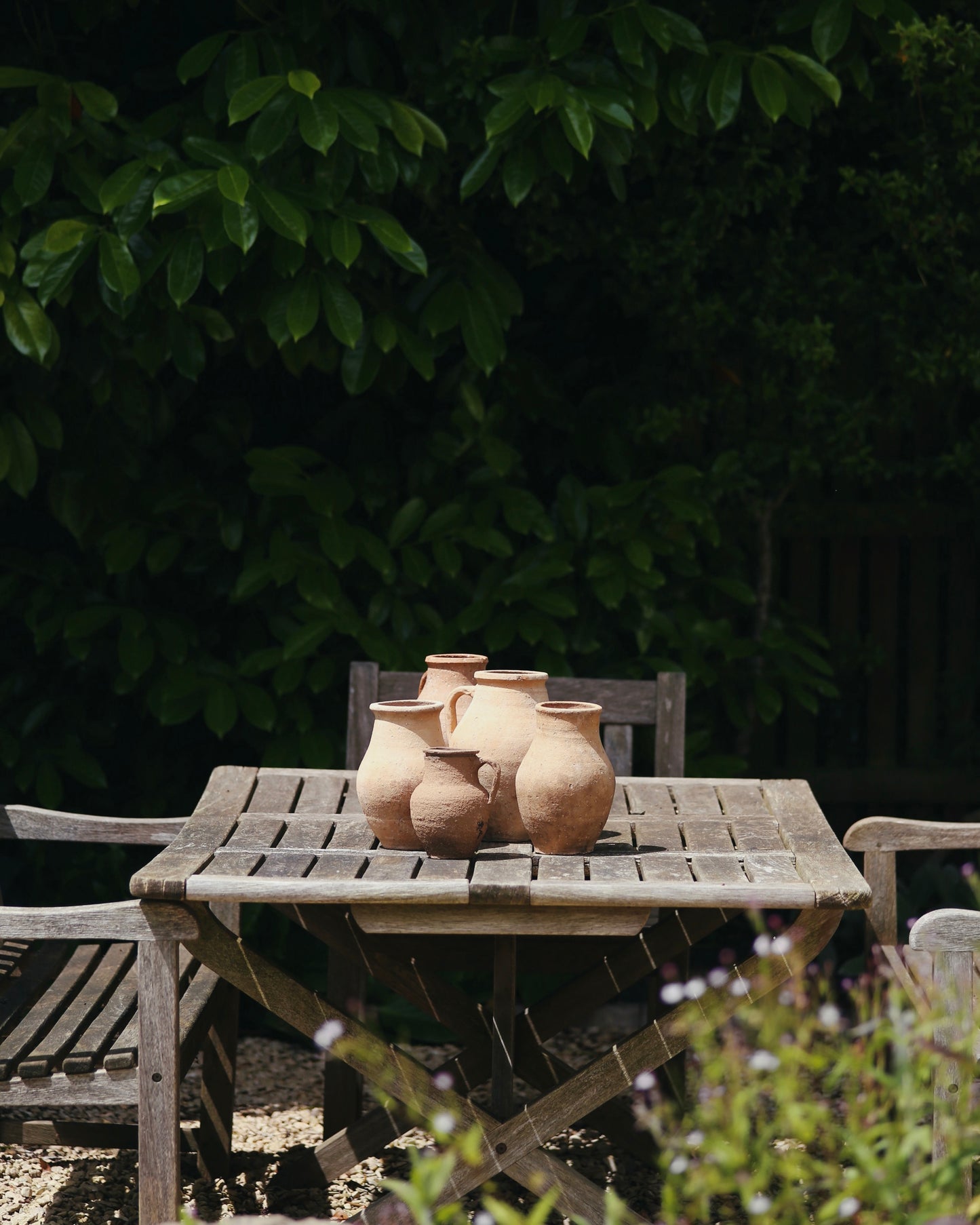 Antique terracotta olive pots sat on rustic wooden table in country garden