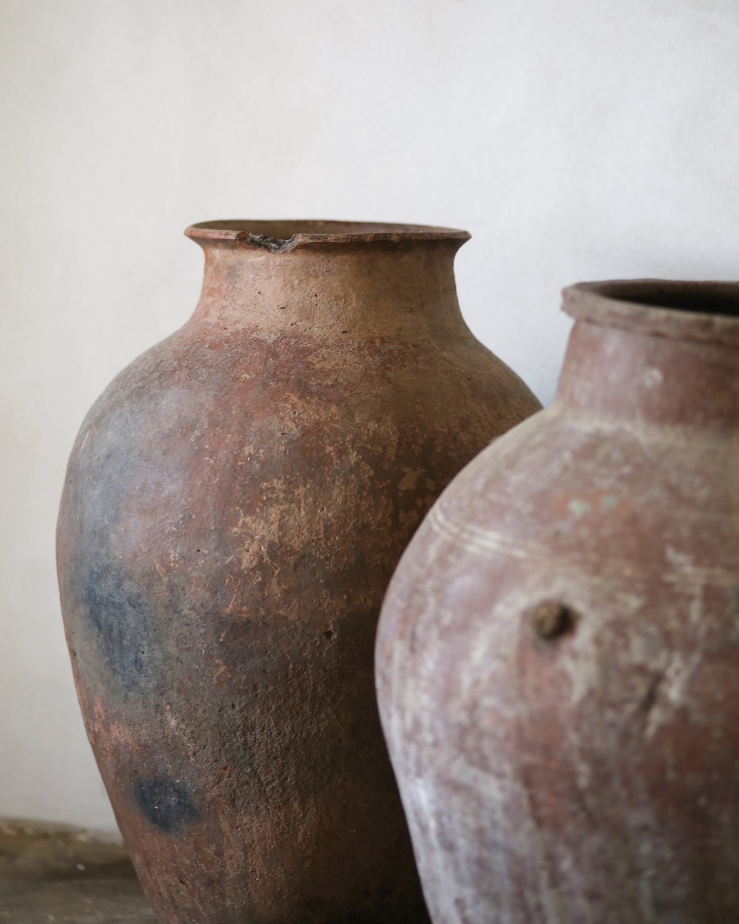 Two rustic clay pots on a plain background