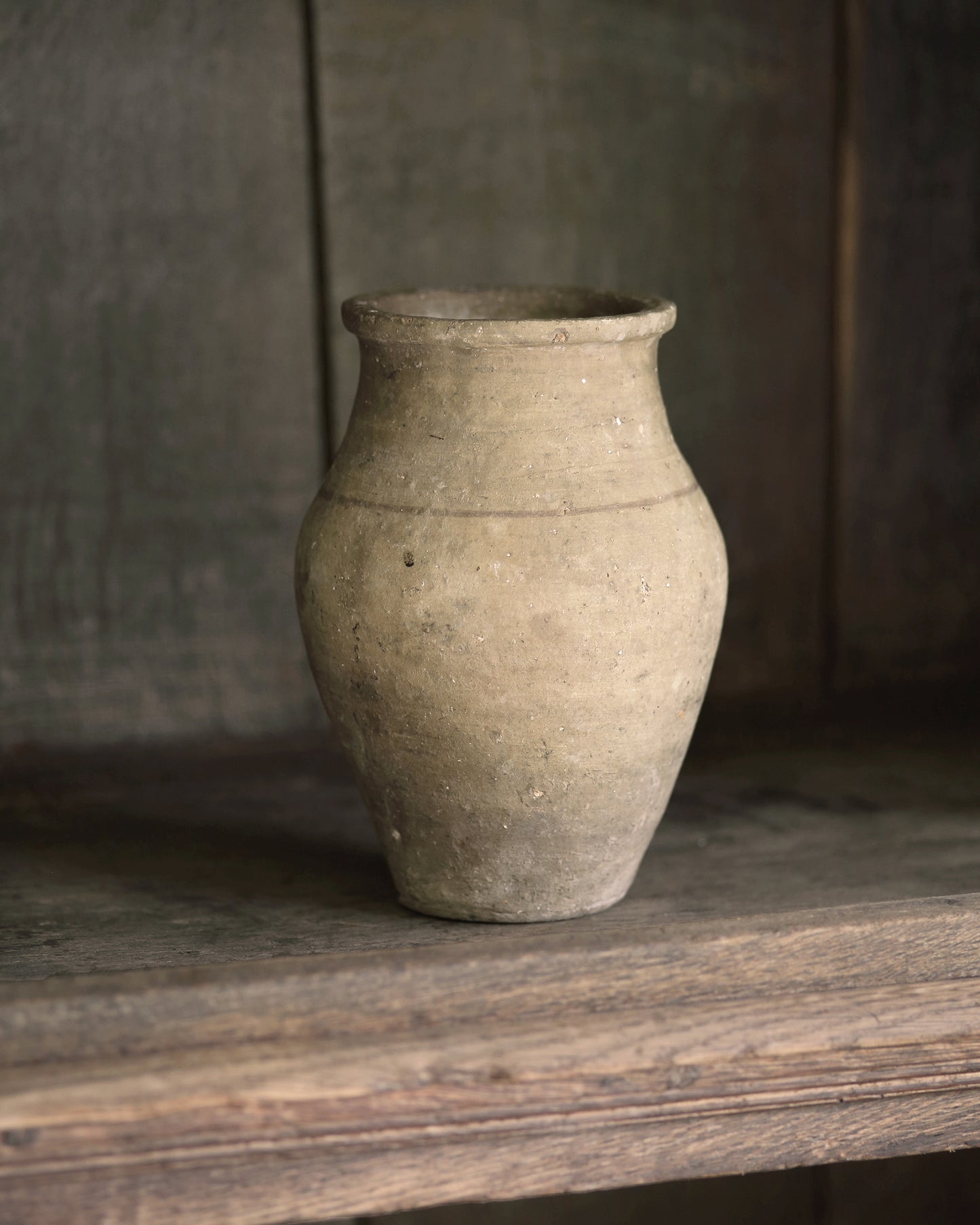 Pale vintage terracotta pot sat in a wooden bookcase