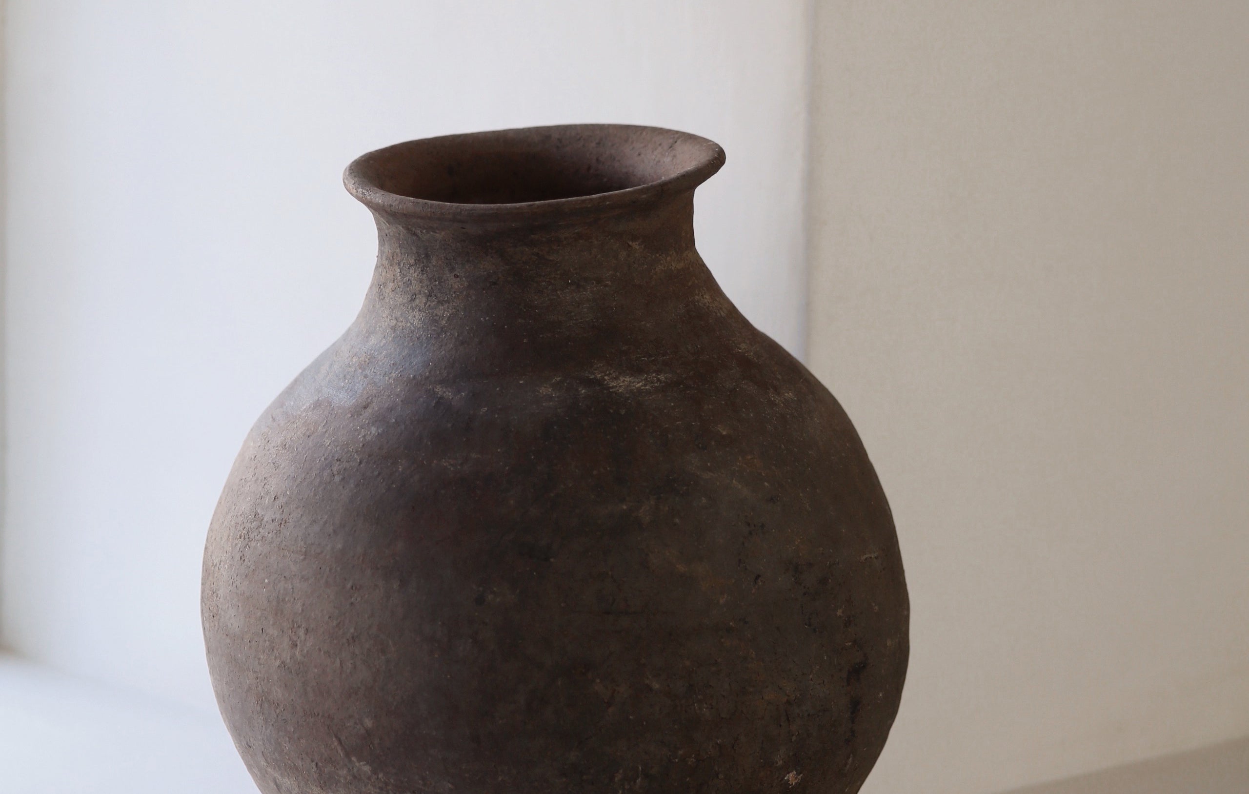 Dark clay pot with rustic aged patina styled in neutral interior
