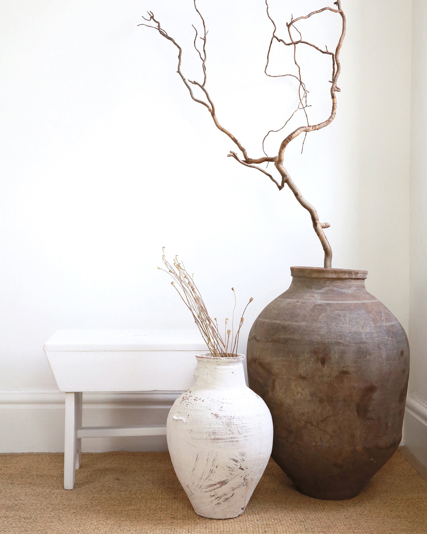 Vintage white milking stool styled with floor standing olive pot and vase