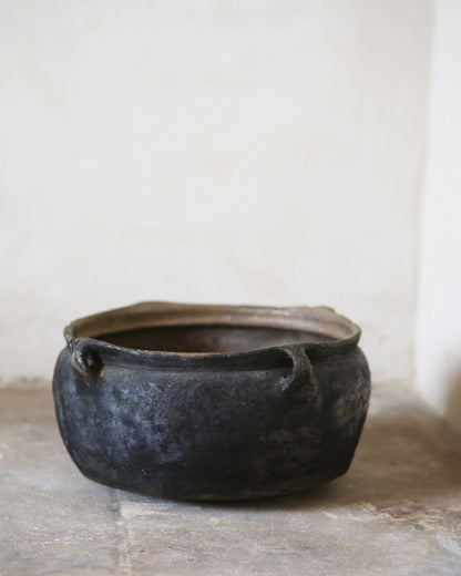 Black ceramic pot on a flagstone surface with a white background