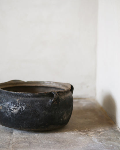 Black pot on a stone surface with a white wall background