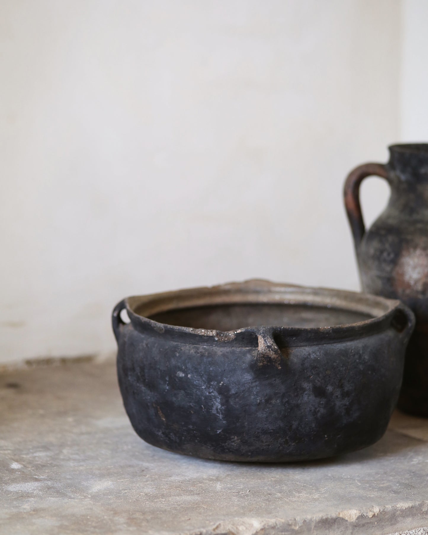 Black ceramic pot on a stone surface with a white background
