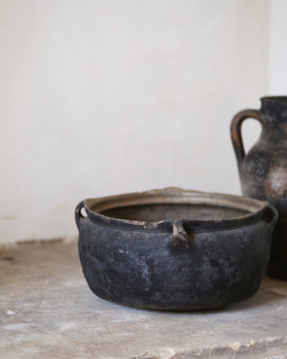 Black ceramic pot on a stone surface with a white background