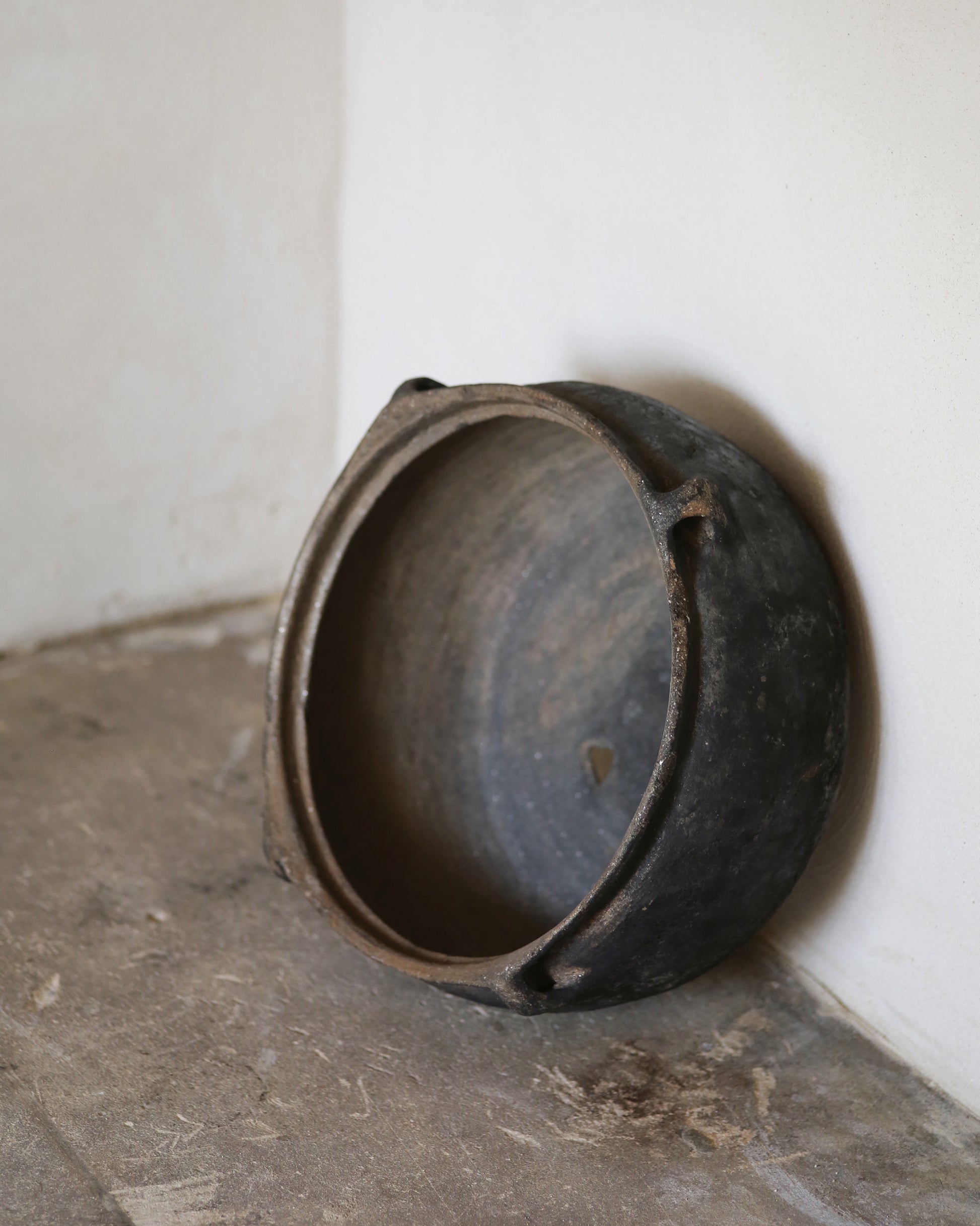 Black pot on a concrete floor against a white wall
