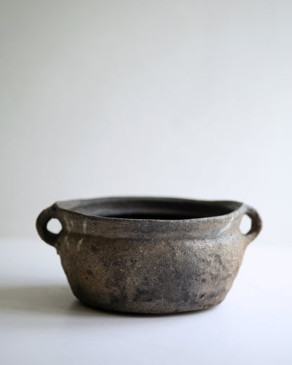 Dark black clay bowl with two small handles to use as a decorative display piece