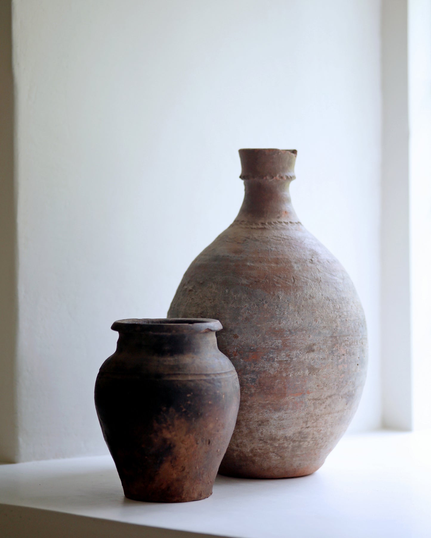 Pairing of dark rustic antique pottery pieces as decorative homeware display