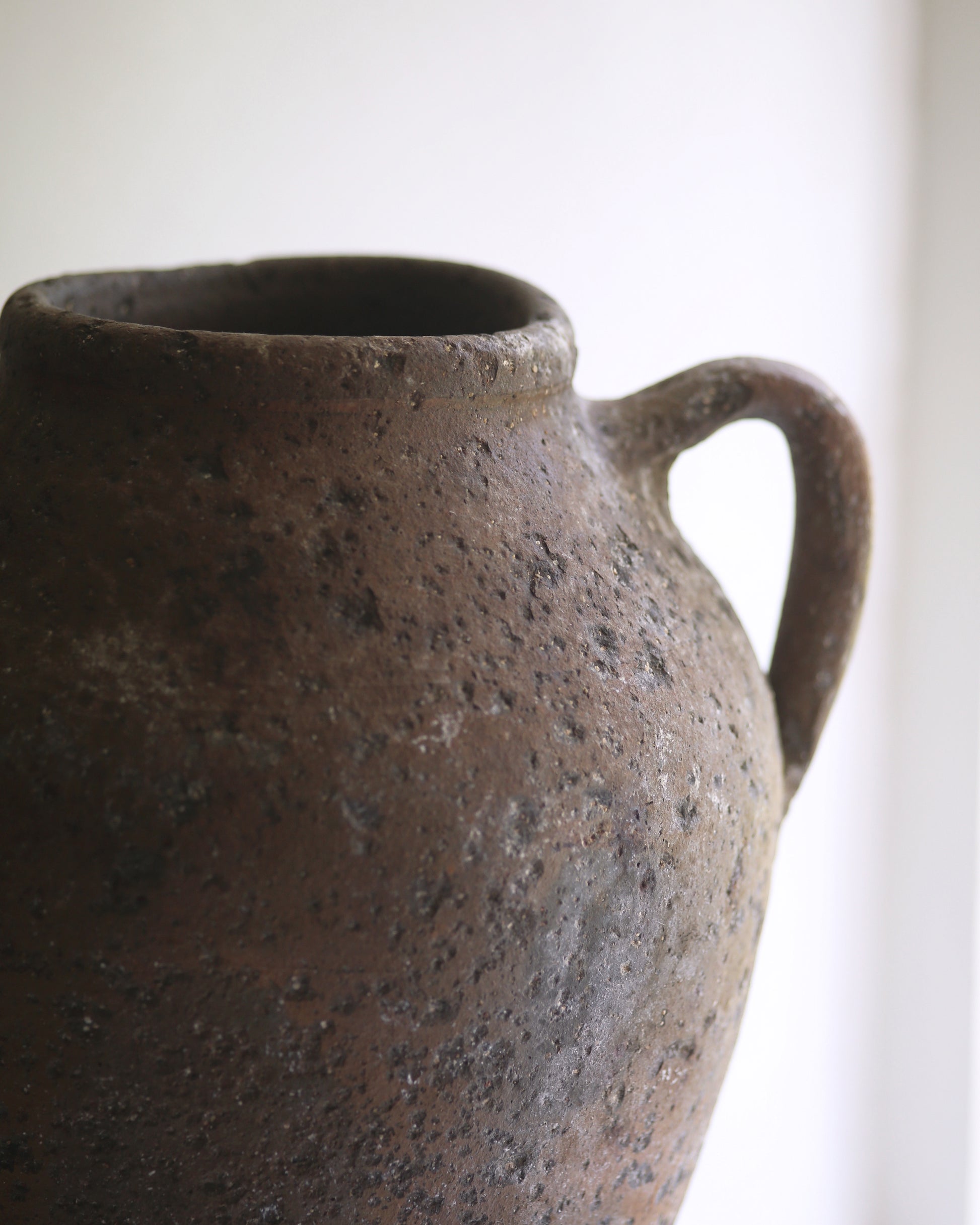 Close up of antique artisan aged clay urn style pottery vase