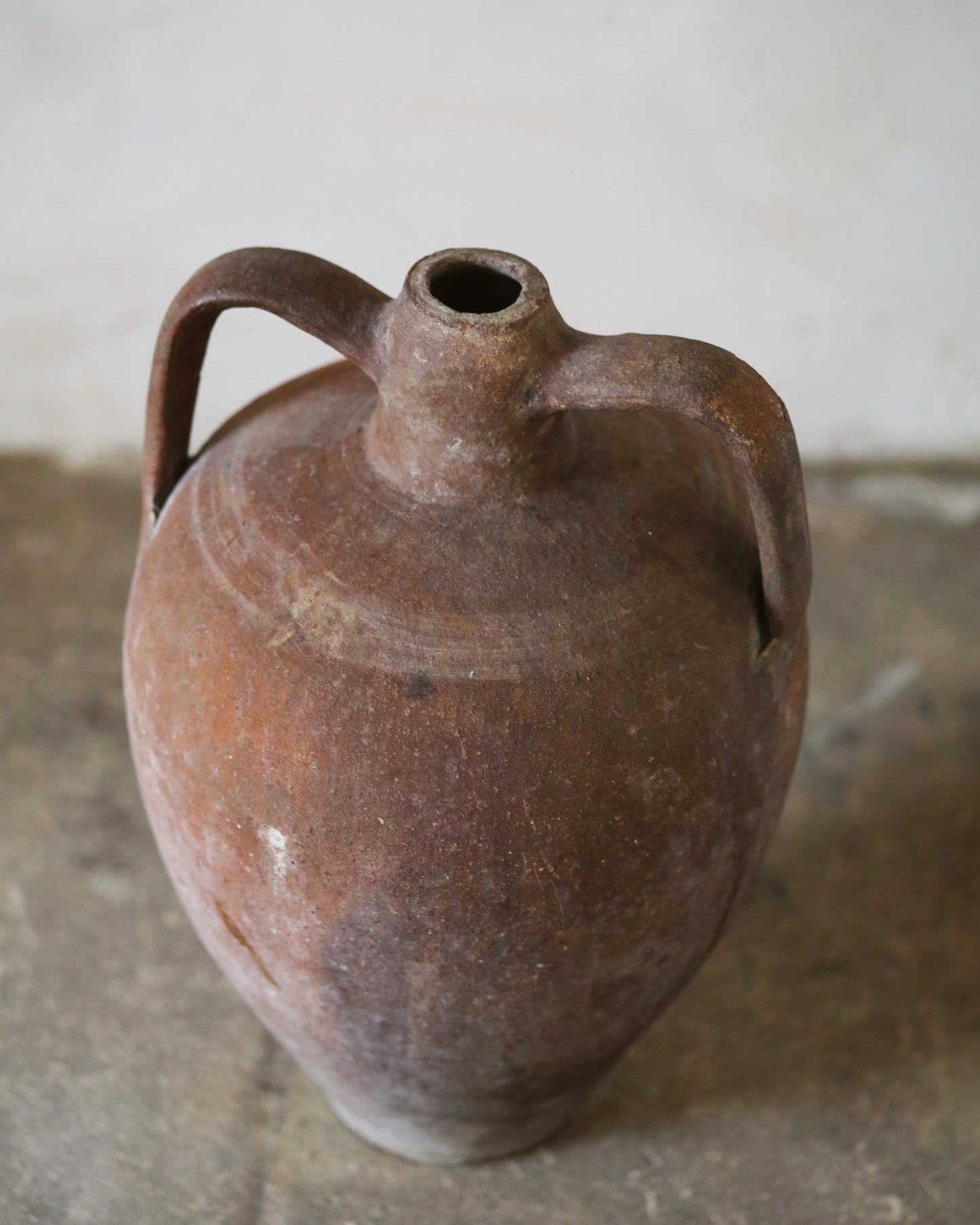Antique Turkish amphora in strong terracotta tones sat on flagstone floor