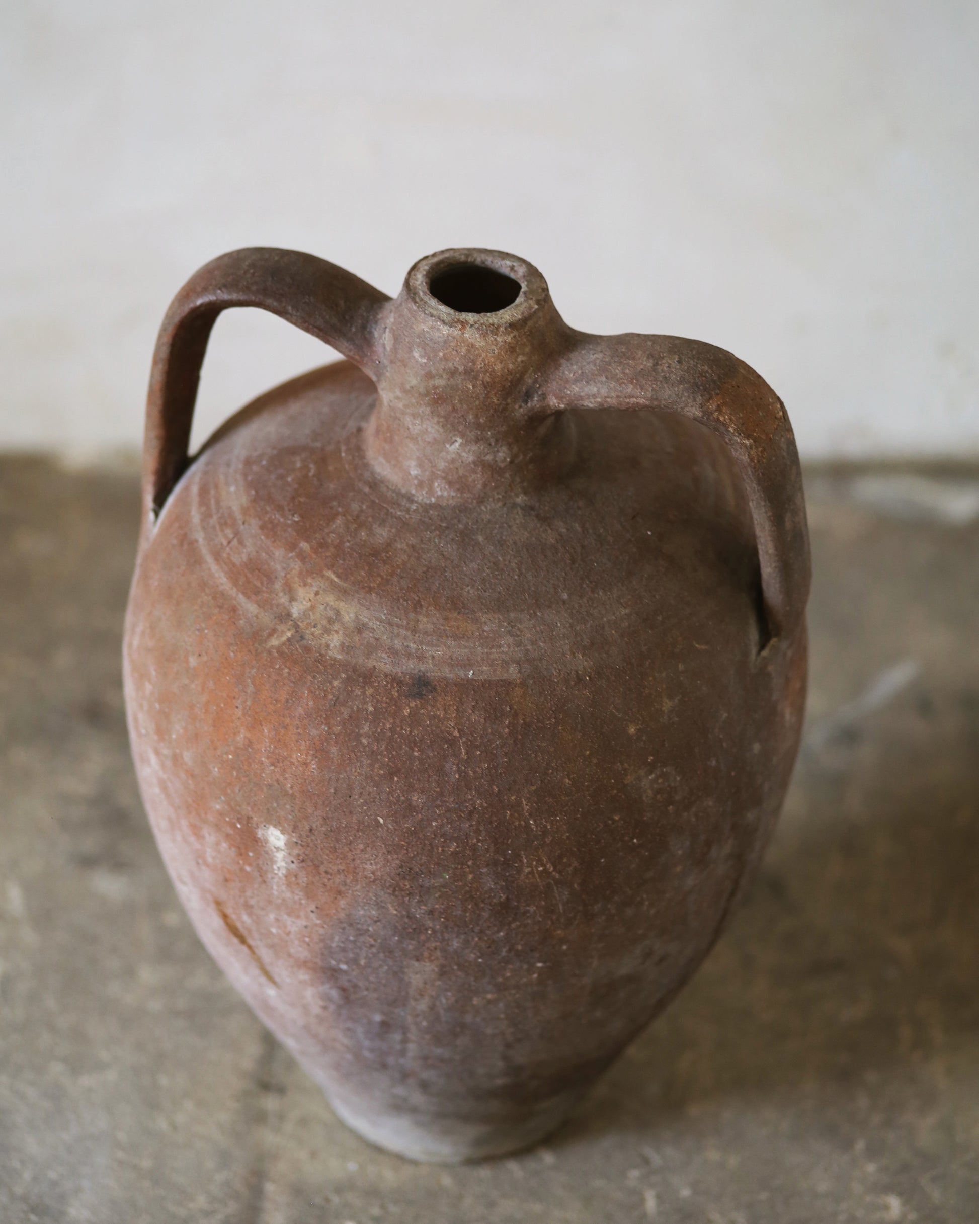 Antique Turkish amphora in strong terracotta tones sat on flagstone floor