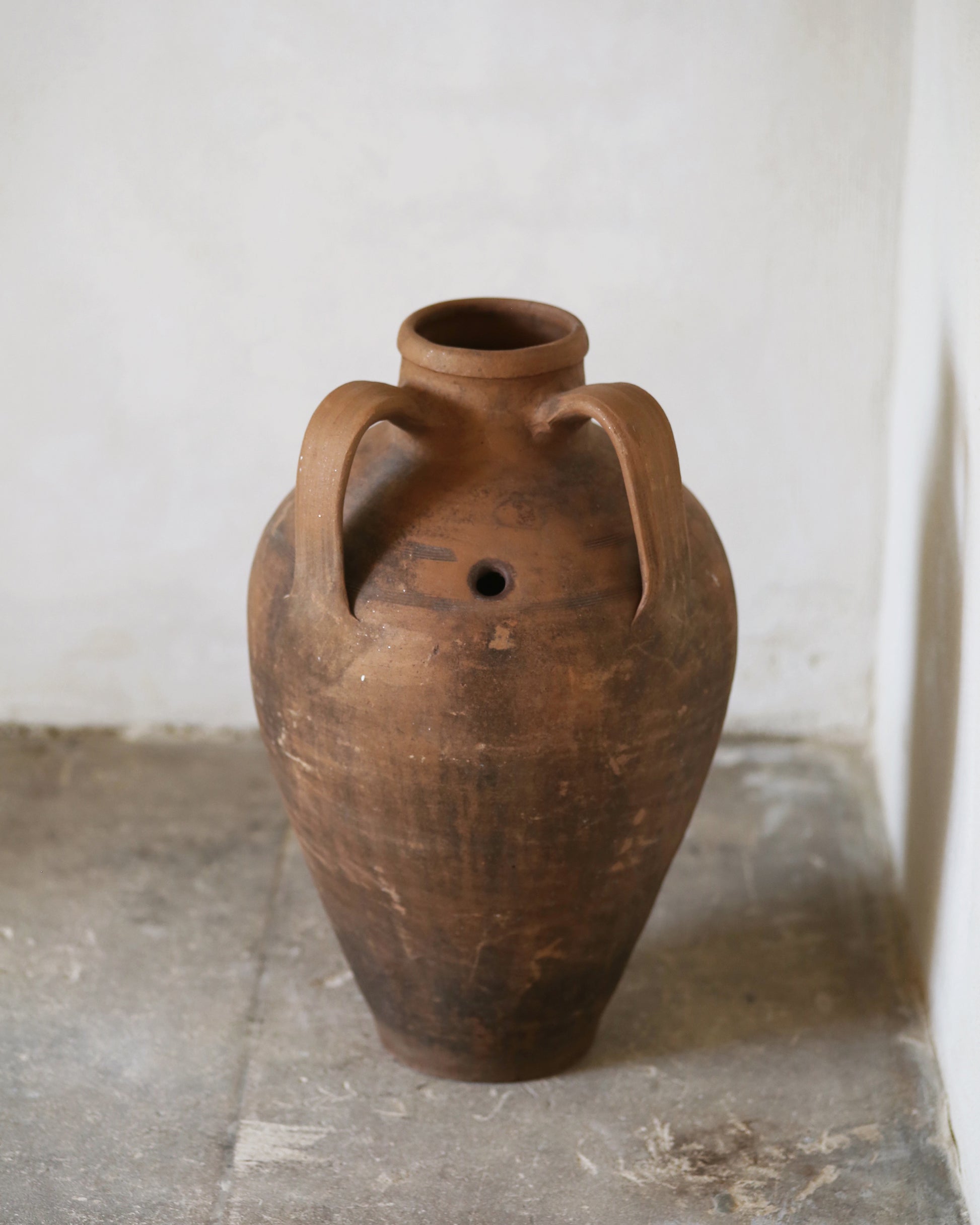Turkish terracotta amphora pot with two handles and a feature of a small hole 