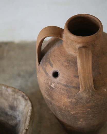 Brown ceramic jug with a handle on a neutral background