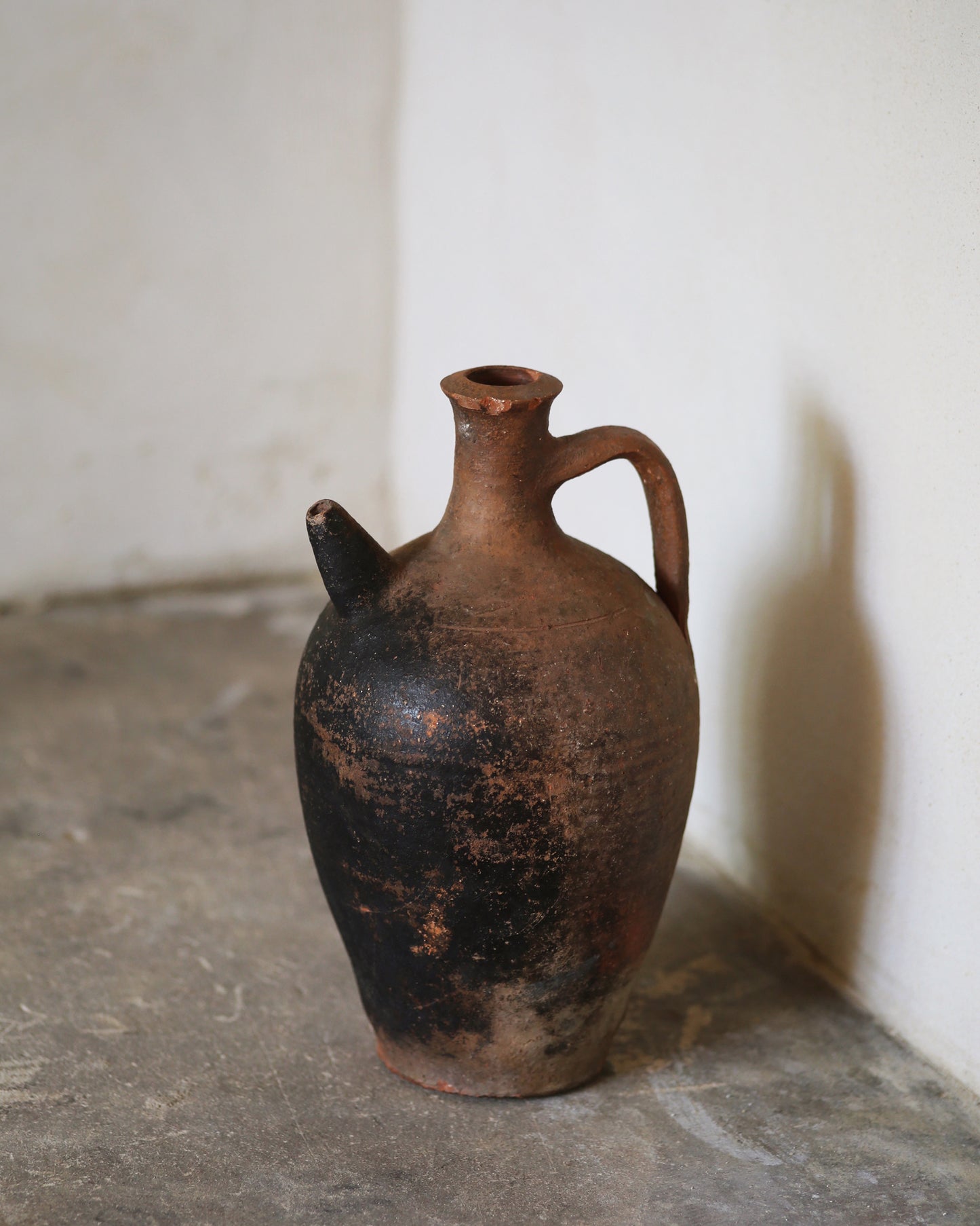 Vintage ceramic jug with a handle on a stone surface.