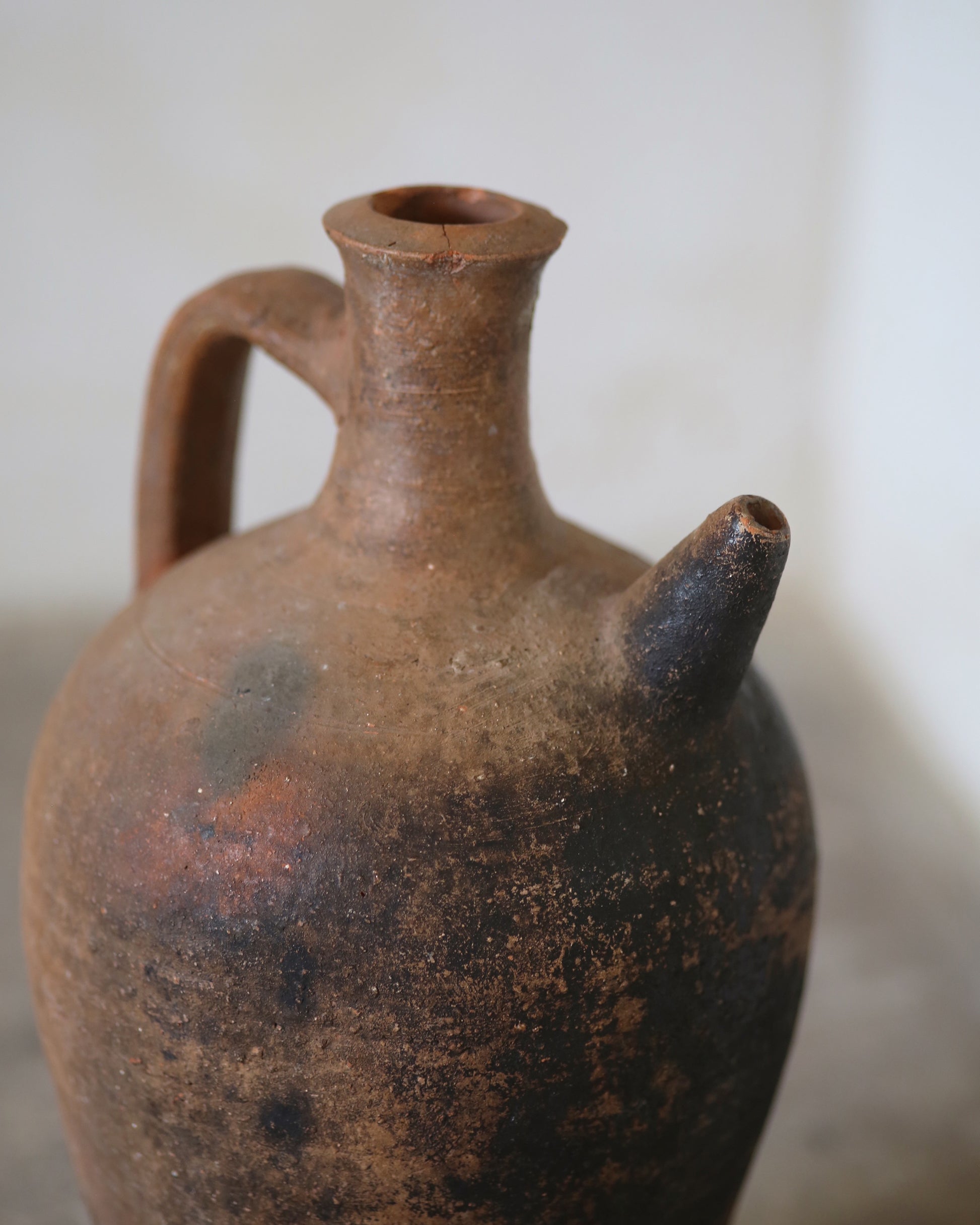Brown ceramic jug with a handle and spout on a light background
