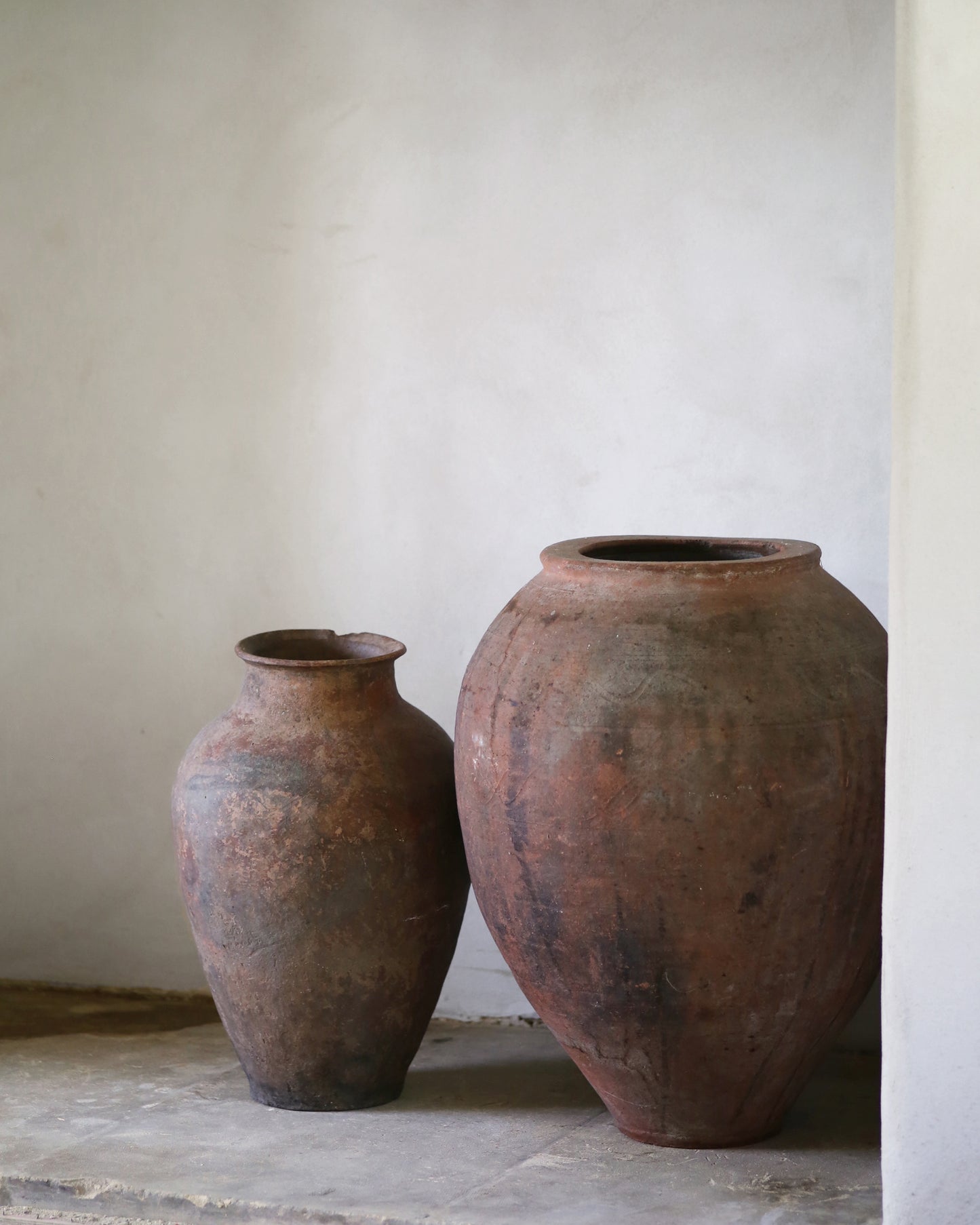 Two rustic antique Turkish clay pots against a plain wall.