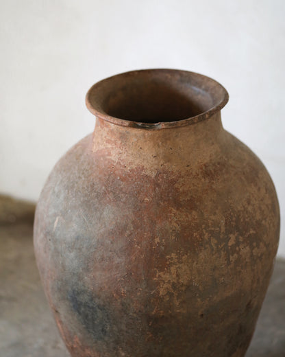 Highly patinaed terracotta pot on a neutral background