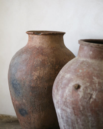 Two rustic clay pots on a plain background