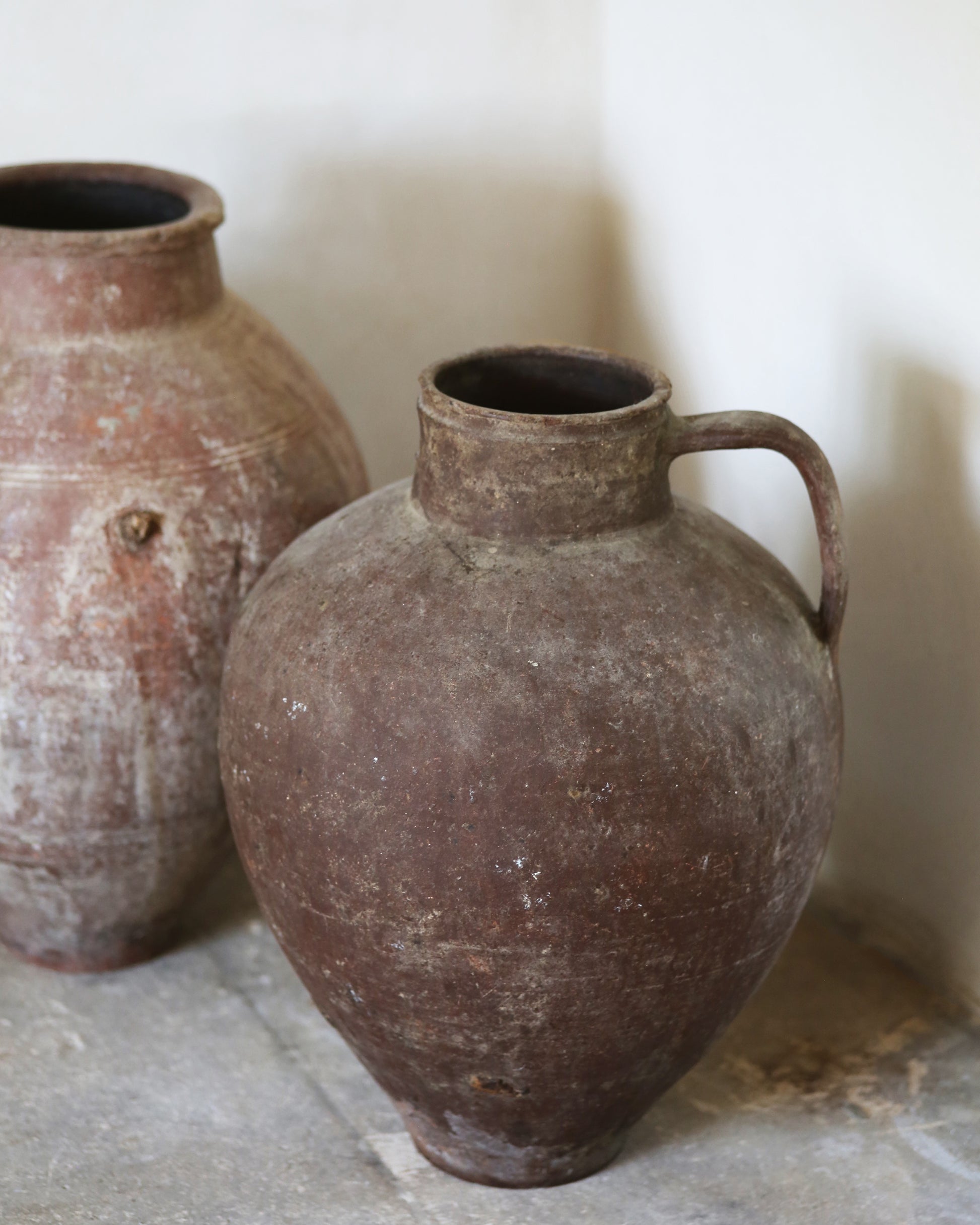 Two rustic clay pots on a stone surface with a neutral background