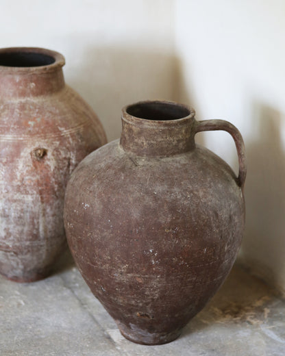 Two rustic clay pots on a stone surface with a neutral background