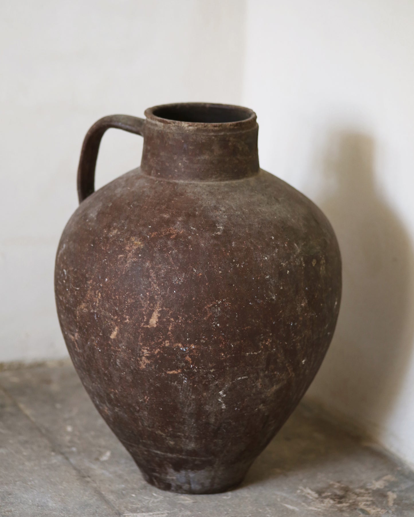 Brown ceramic olive pot on a stone surface with a white background