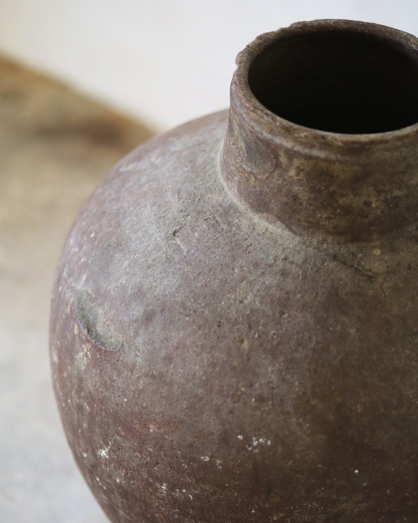 Close-up of a textured brown ceramic vase on a light background
