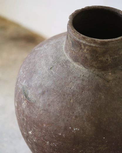 Close-up of a textured brown ceramic vase on a light background