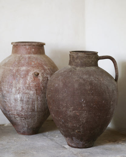 Two rustic clay pots on a flagstone surface with a white background