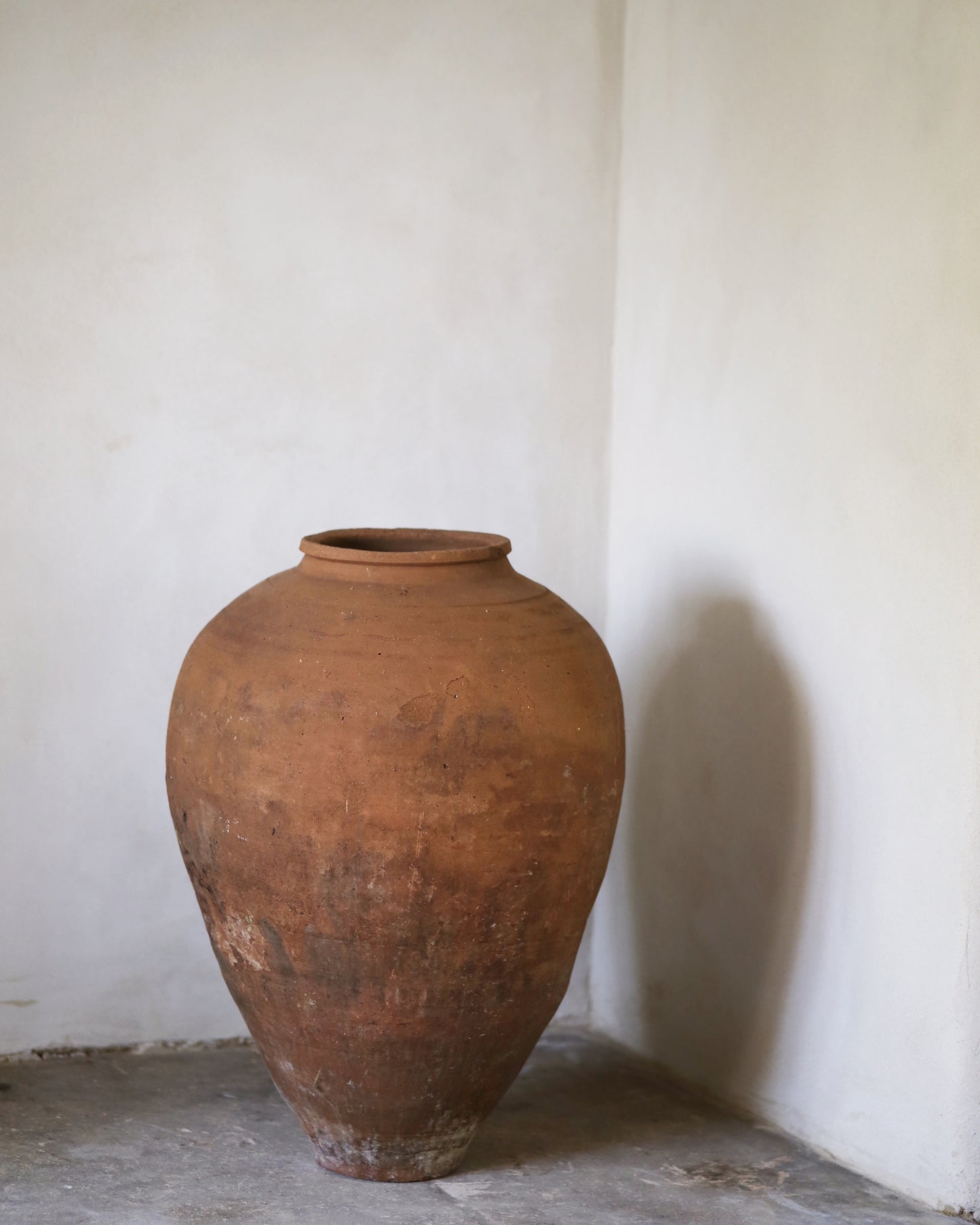 Large brown ceramic jar against a white wall