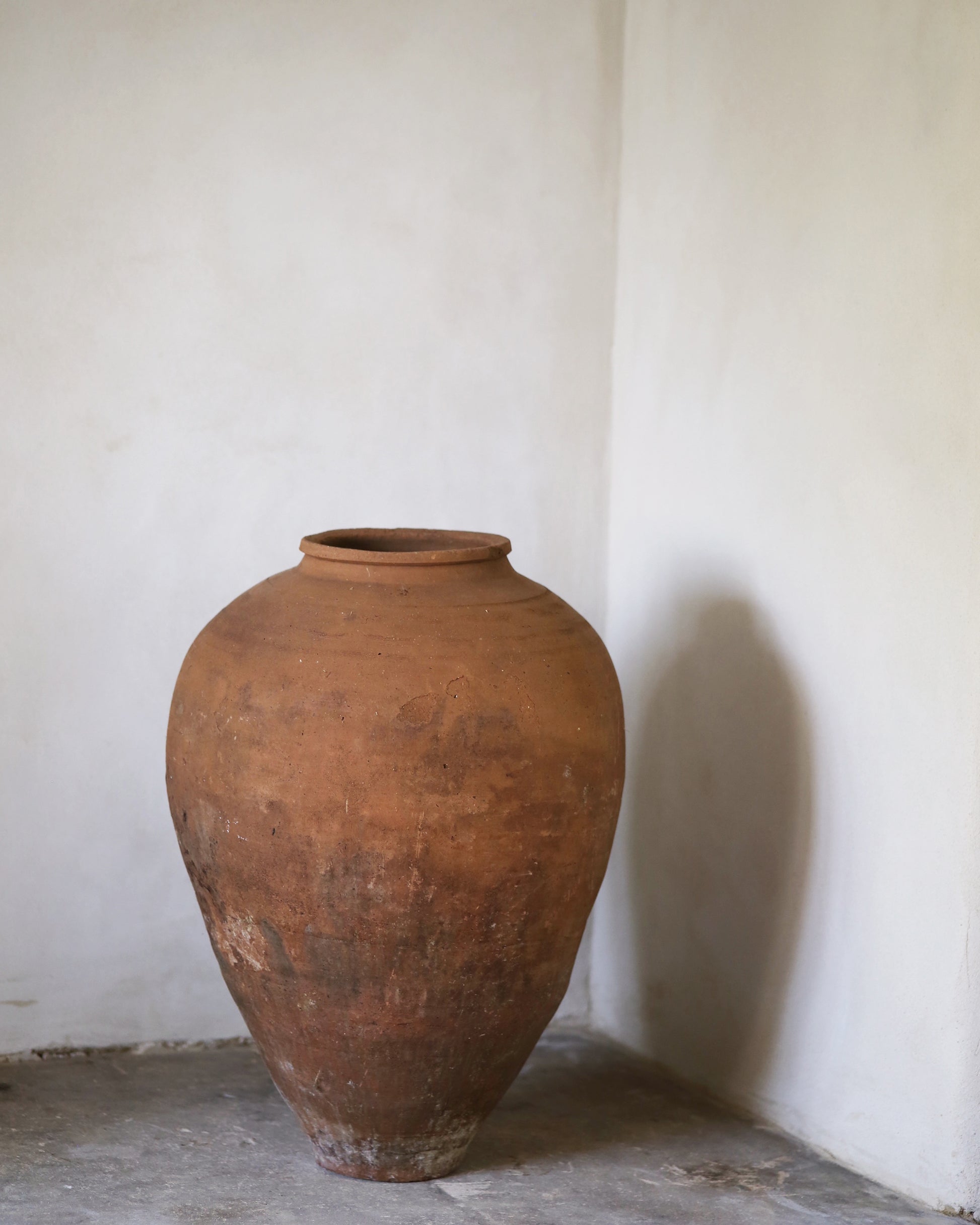 Large brown ceramic jar against a white wall