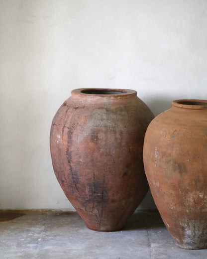 Two large terracotta pots on a stone surface with a plain background