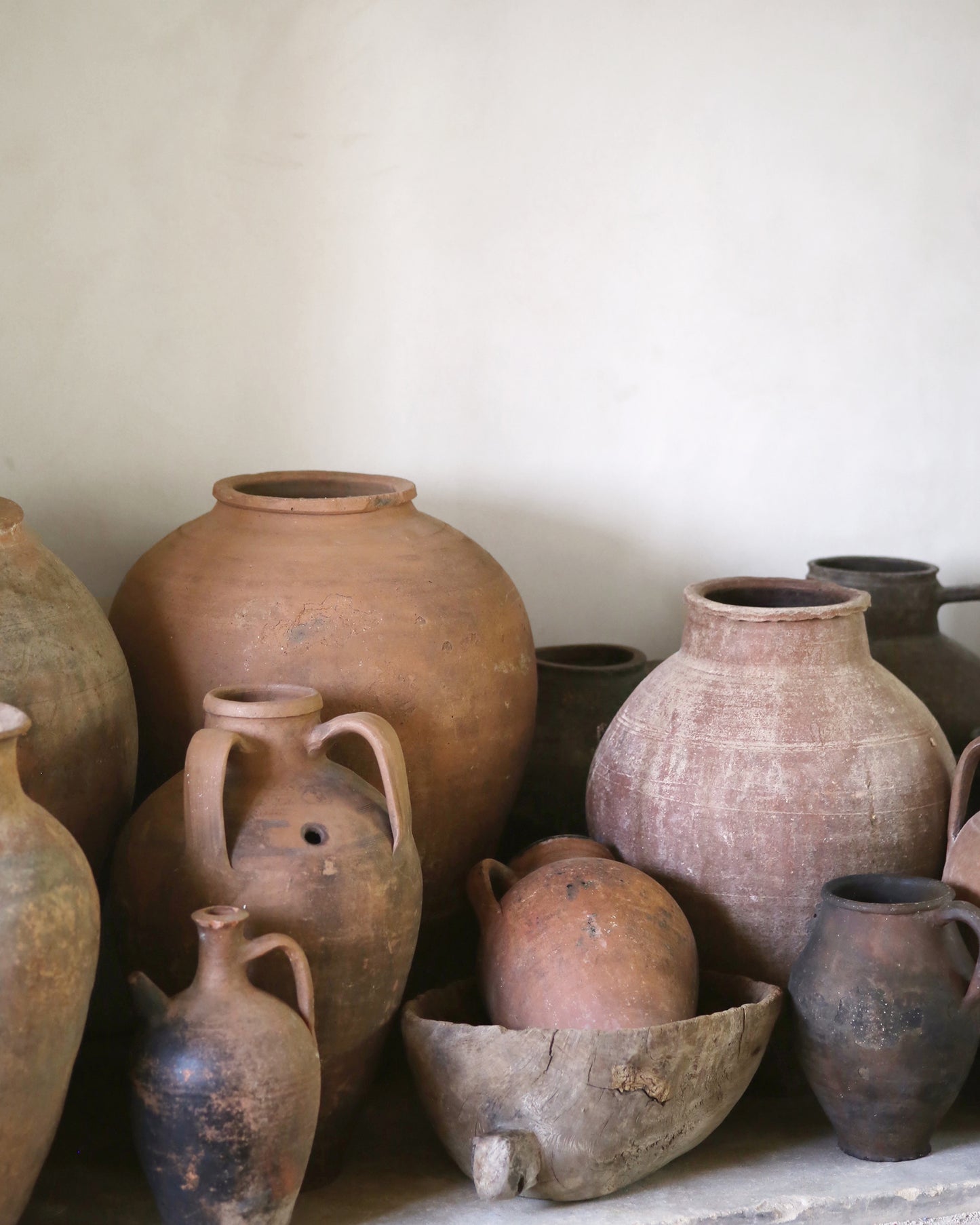 Collection of various terracotta pots and jars on a light background