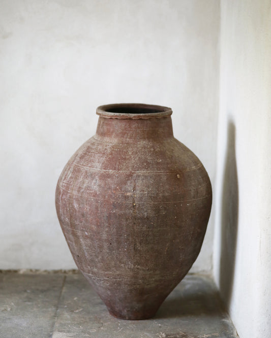 Large brown ceramic vase against a plain white wall