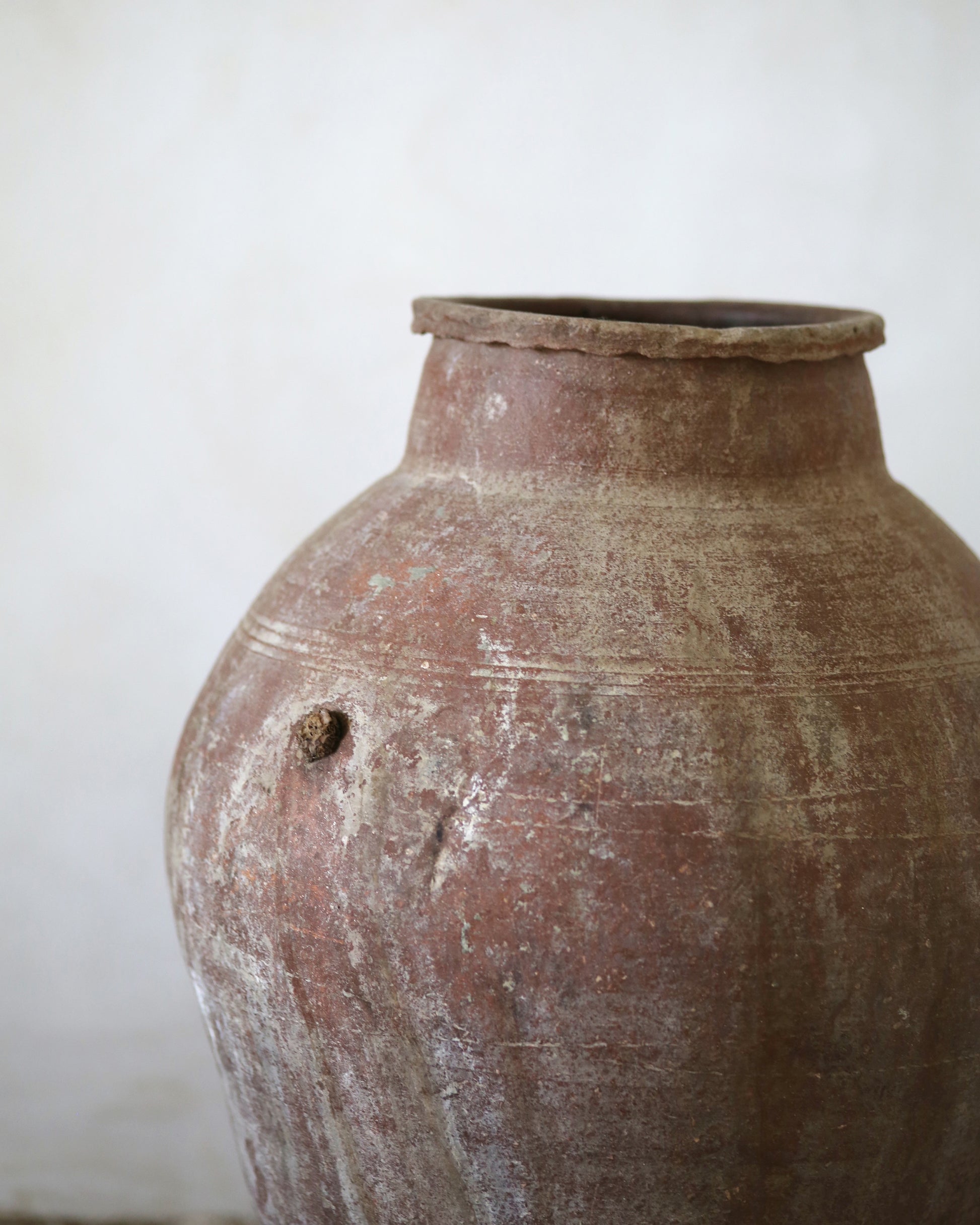 Brown ceramic olive jar with a textured surface on a white background