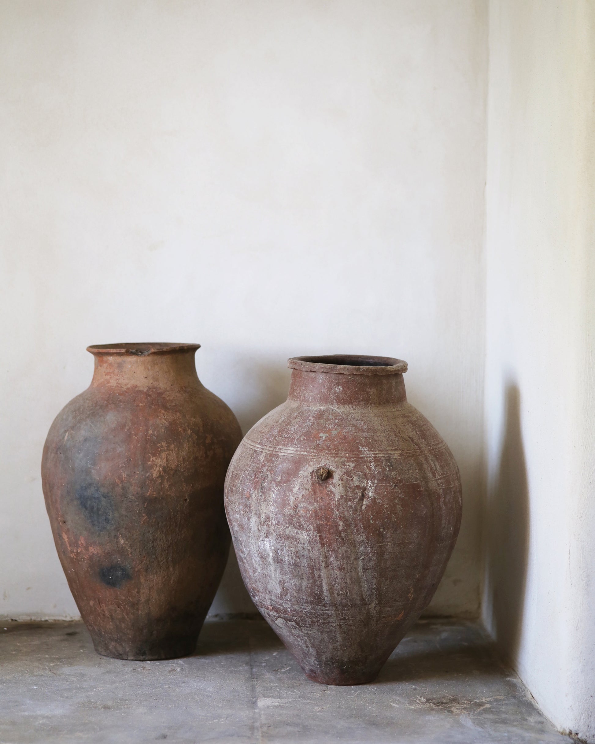 Two rustic clay pots against a plain wall.