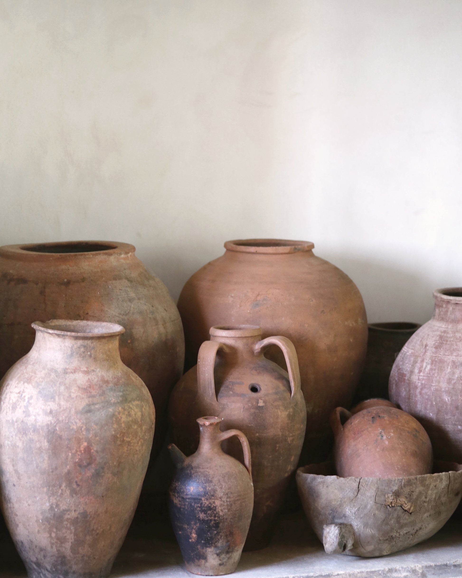 Collection of various terracotta pots and jars on a light background