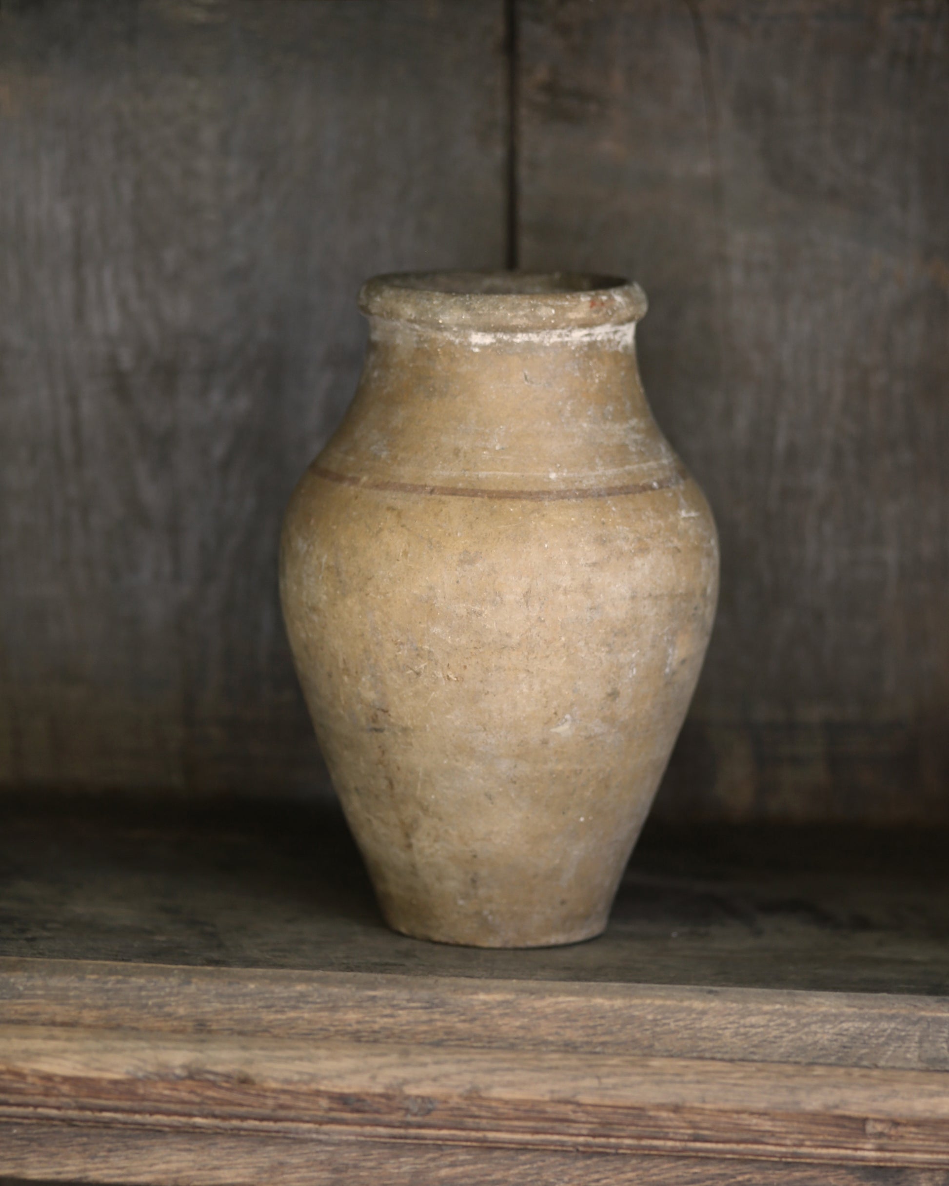 Rustic aged vintage mediterranean clay pottery vase on a wooden bookcase