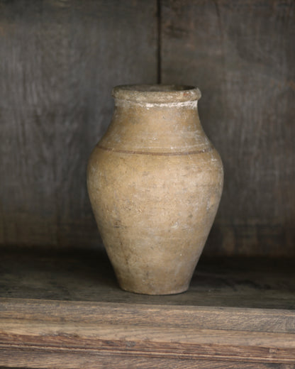 Rustic aged vintage mediterranean clay pottery vase on a wooden bookcase