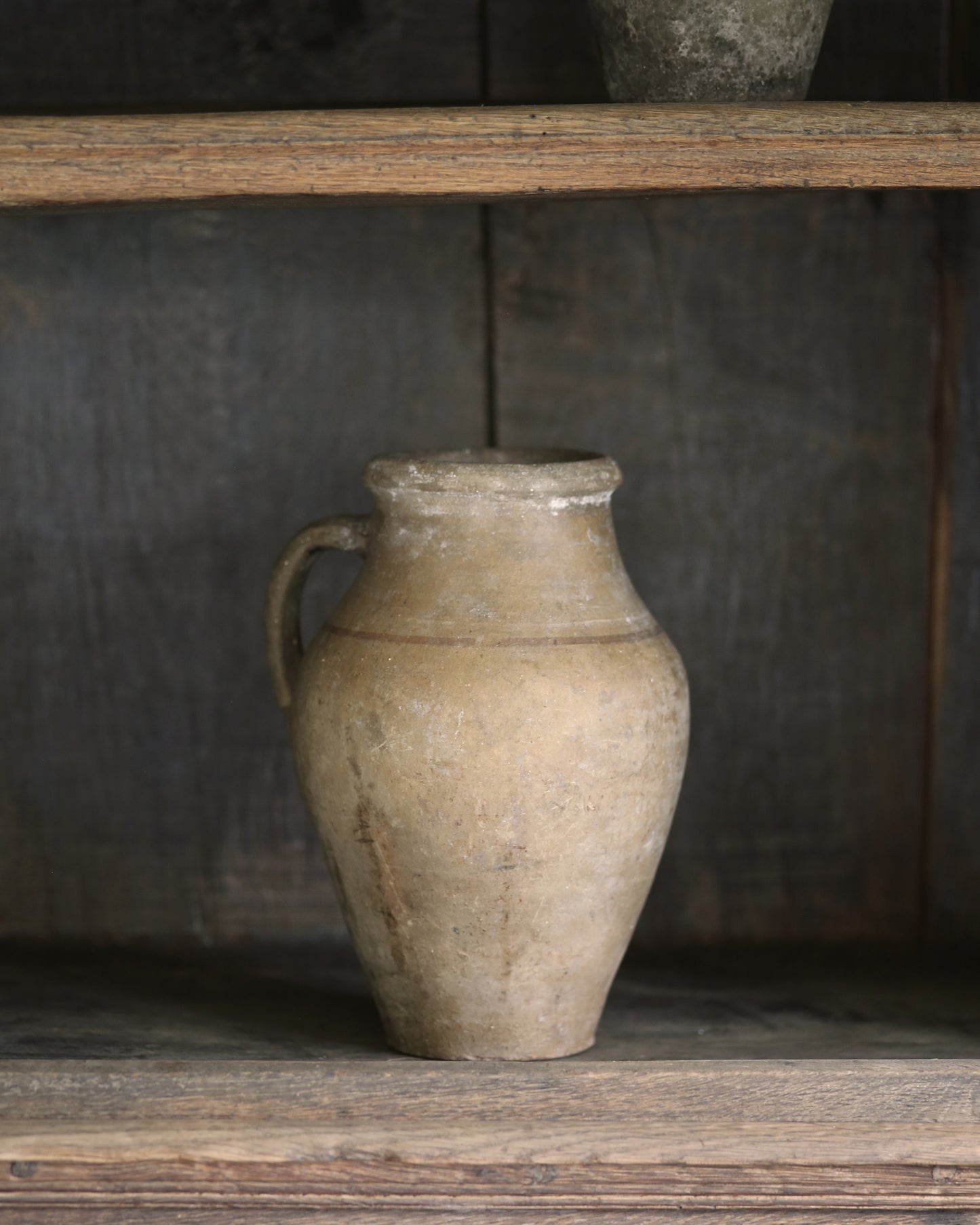 Vintage-style ceramic pitcher pot styled on an antique wooden bookcase