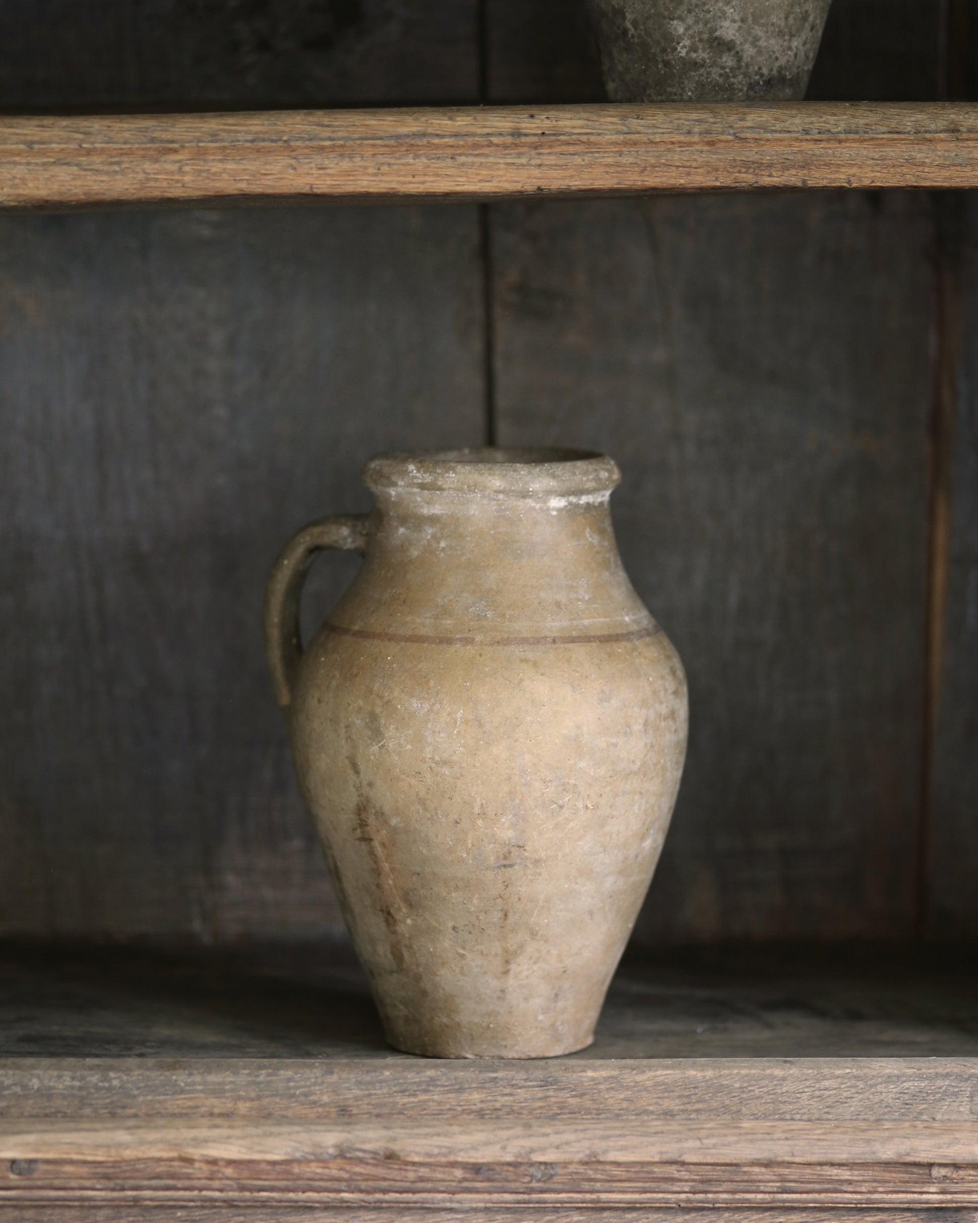 Vintage-style ceramic pitcher pot styled on an antique wooden bookcase