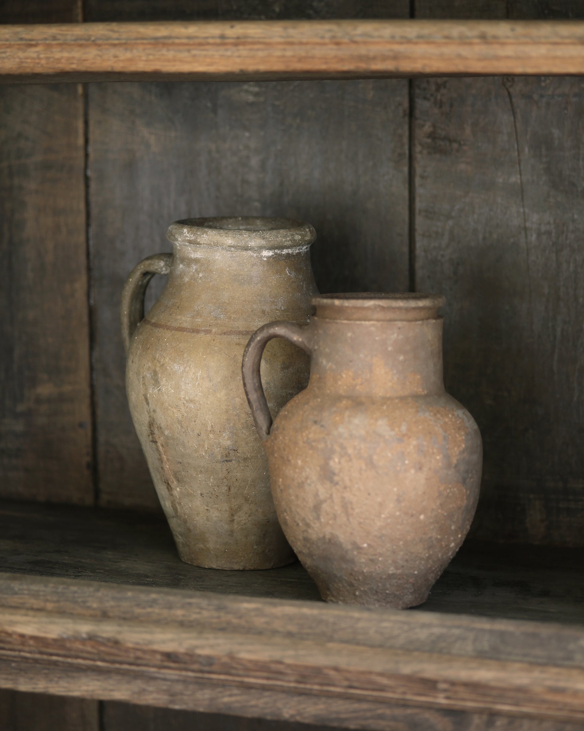 Two rustic clay Turkish pots styled on a wooden shelf 