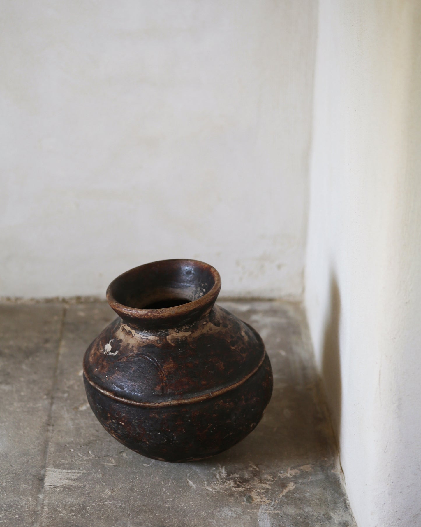 Rich brown ceramic antique terracotta pot sat on flagstone surface