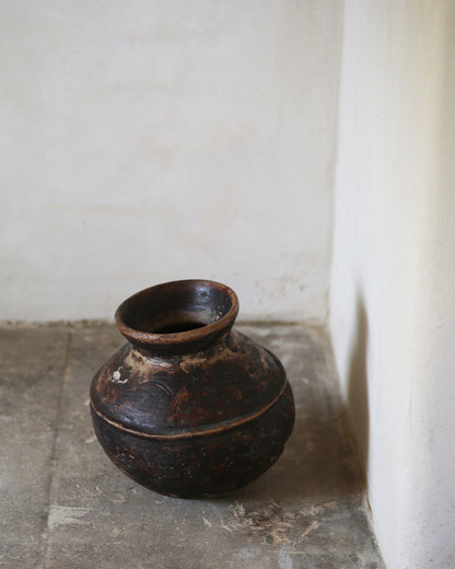 Rich brown ceramic antique terracotta pot sat on flagstone surface