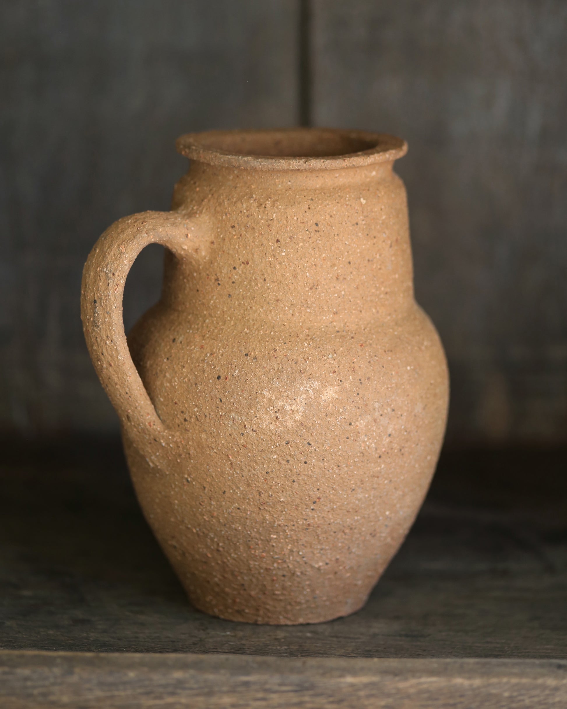 Brown ceramic pitcher on a dark wooden surface 
