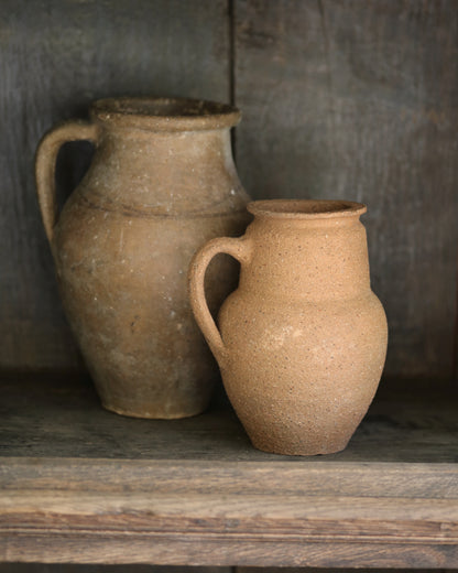 Two rustic clay jars on a wooden surface with a dark background