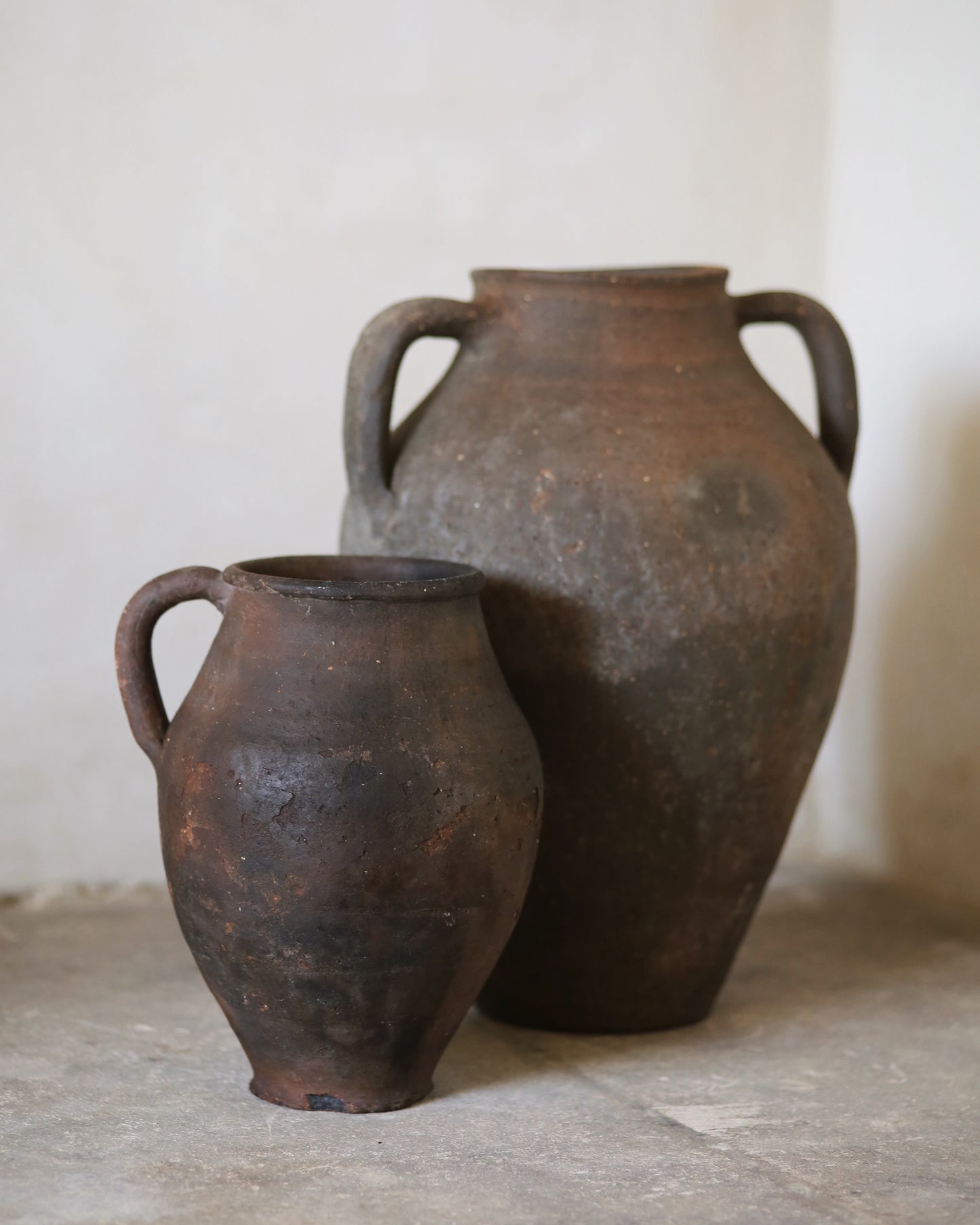 Two rustic clay pots on a neutral background