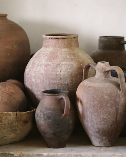 Collection of Antique rustic clay pots and jars on a neutral background