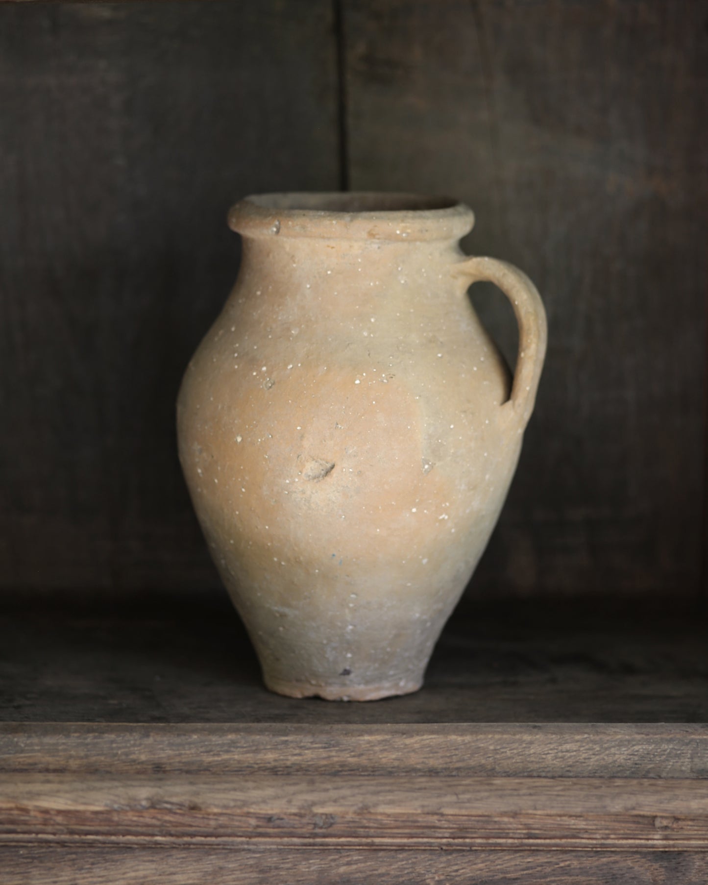 Vintage terracotta pot with a handle on a wooden surface