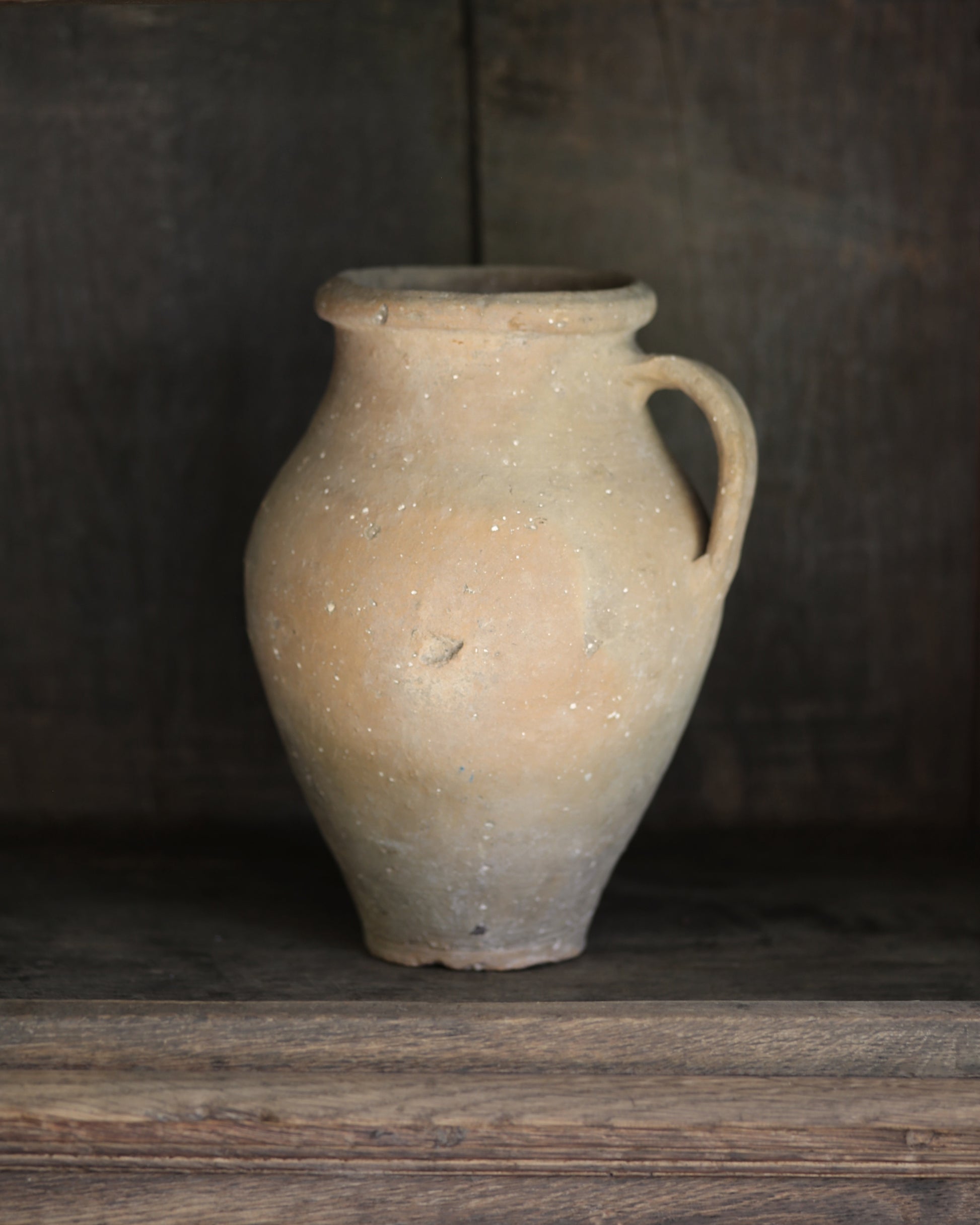 Vintage terracotta pot with a handle on a wooden surface